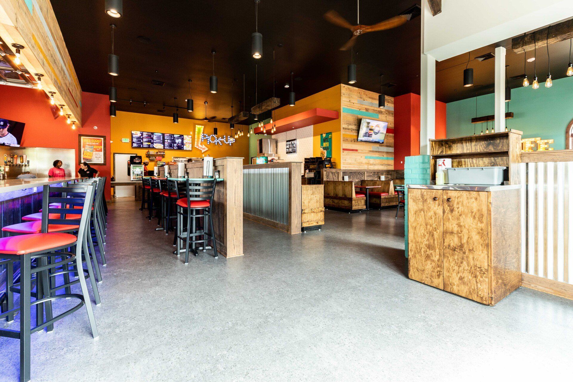 A restaurant with a lot of tables and chairs and a ceiling fan.