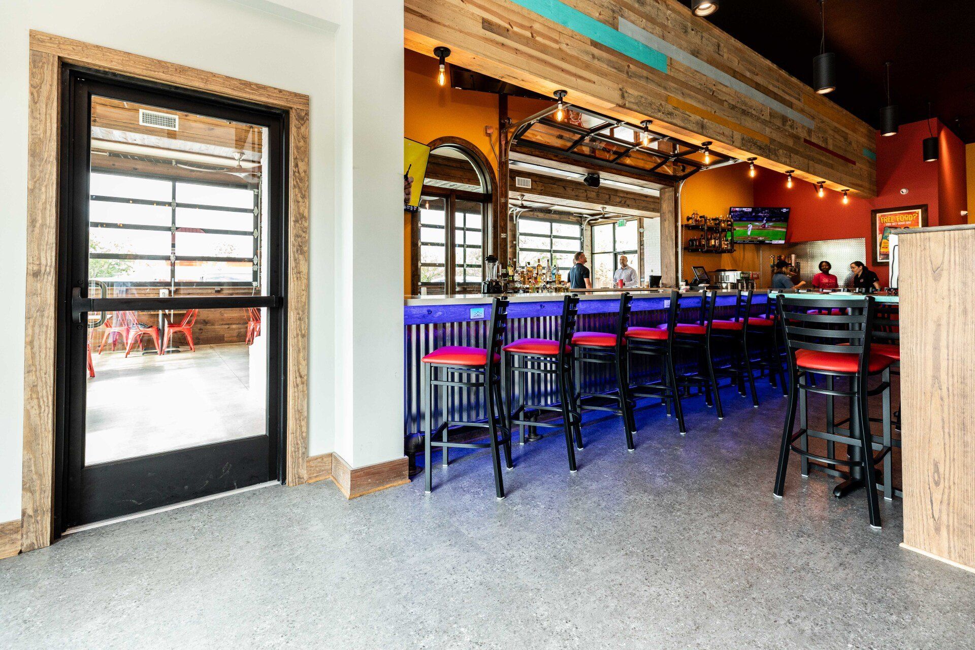 A restaurant with a bar and stools and a large window.