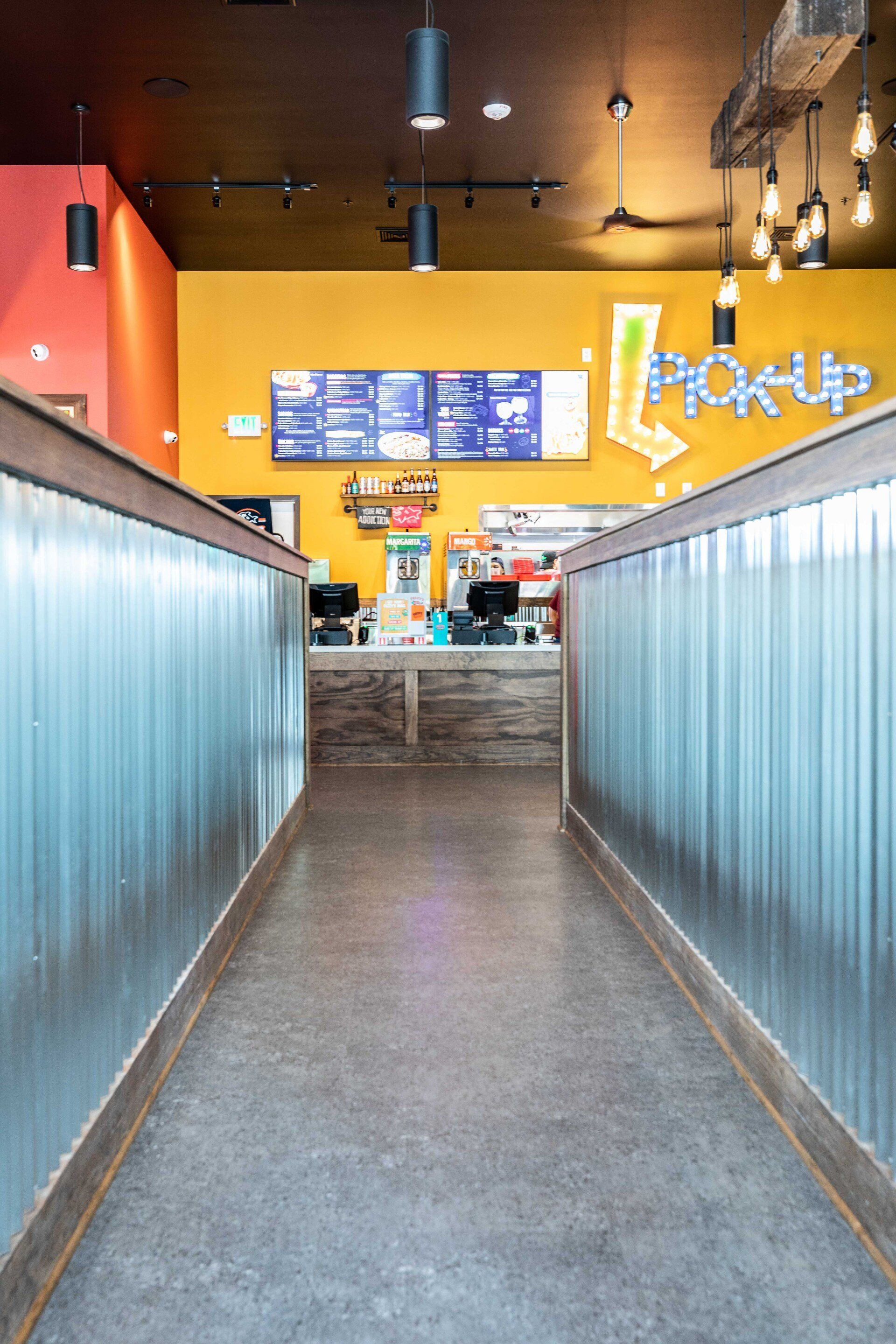 A long hallway leading to a counter in a restaurant.