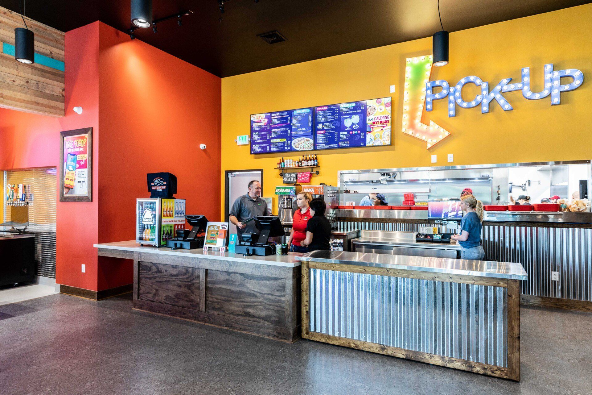 A couple of people are standing at a counter in a restaurant.