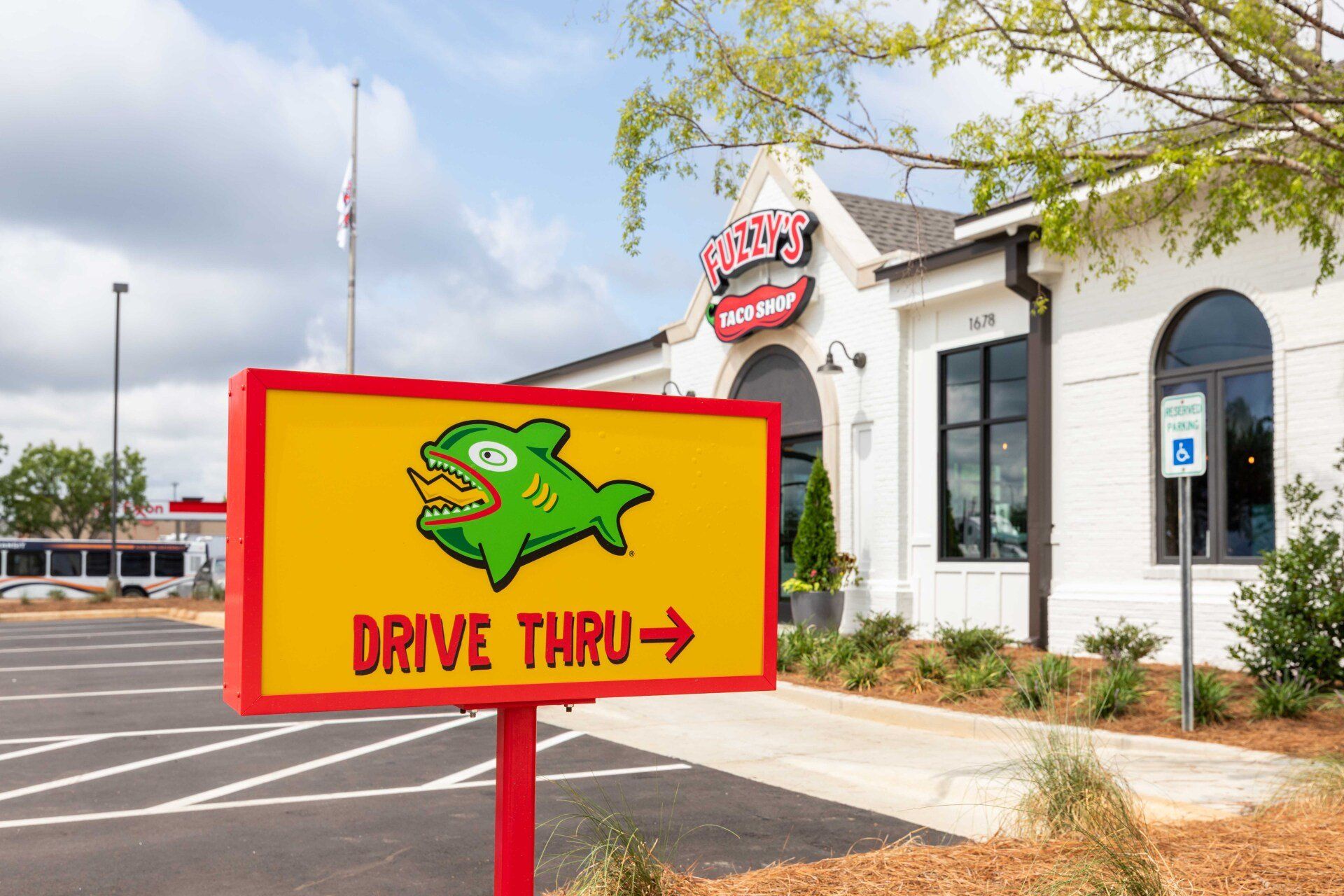 A yellow sign with a green fish on it is in front of a restaurant.