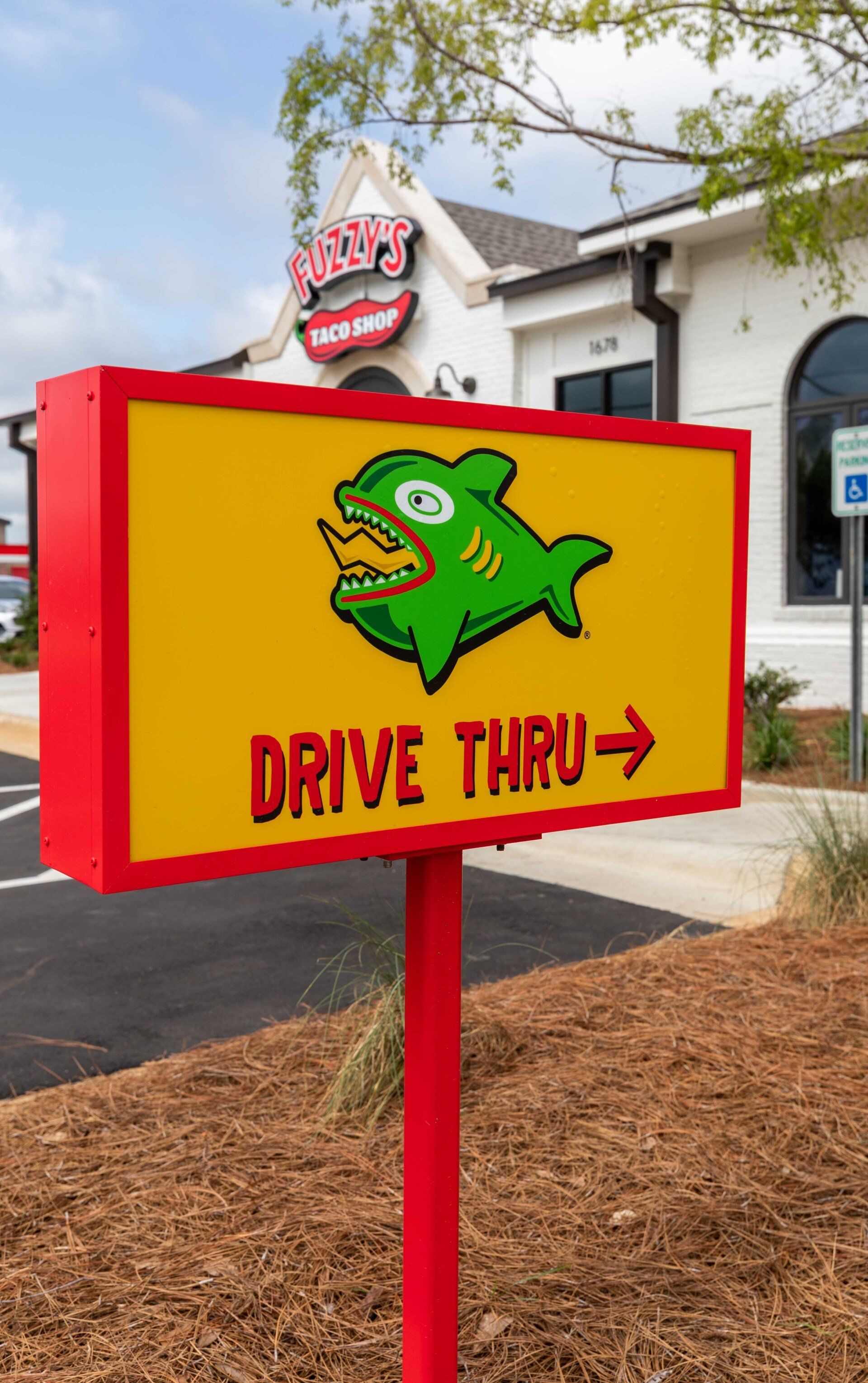 A yellow sign with a green fish on it says drive thru.