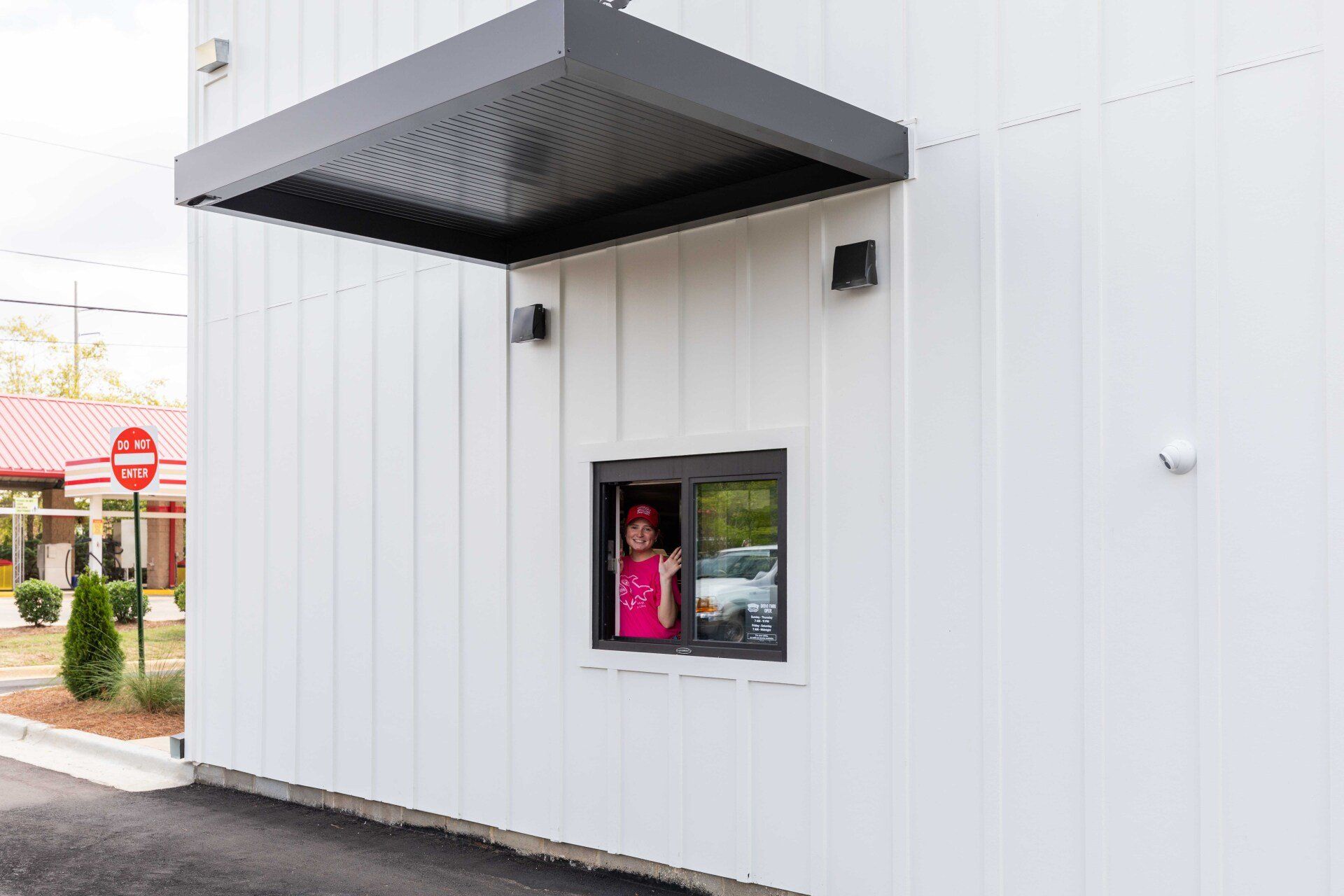 A woman is standing in a drive thru window at a fast food restaurant.