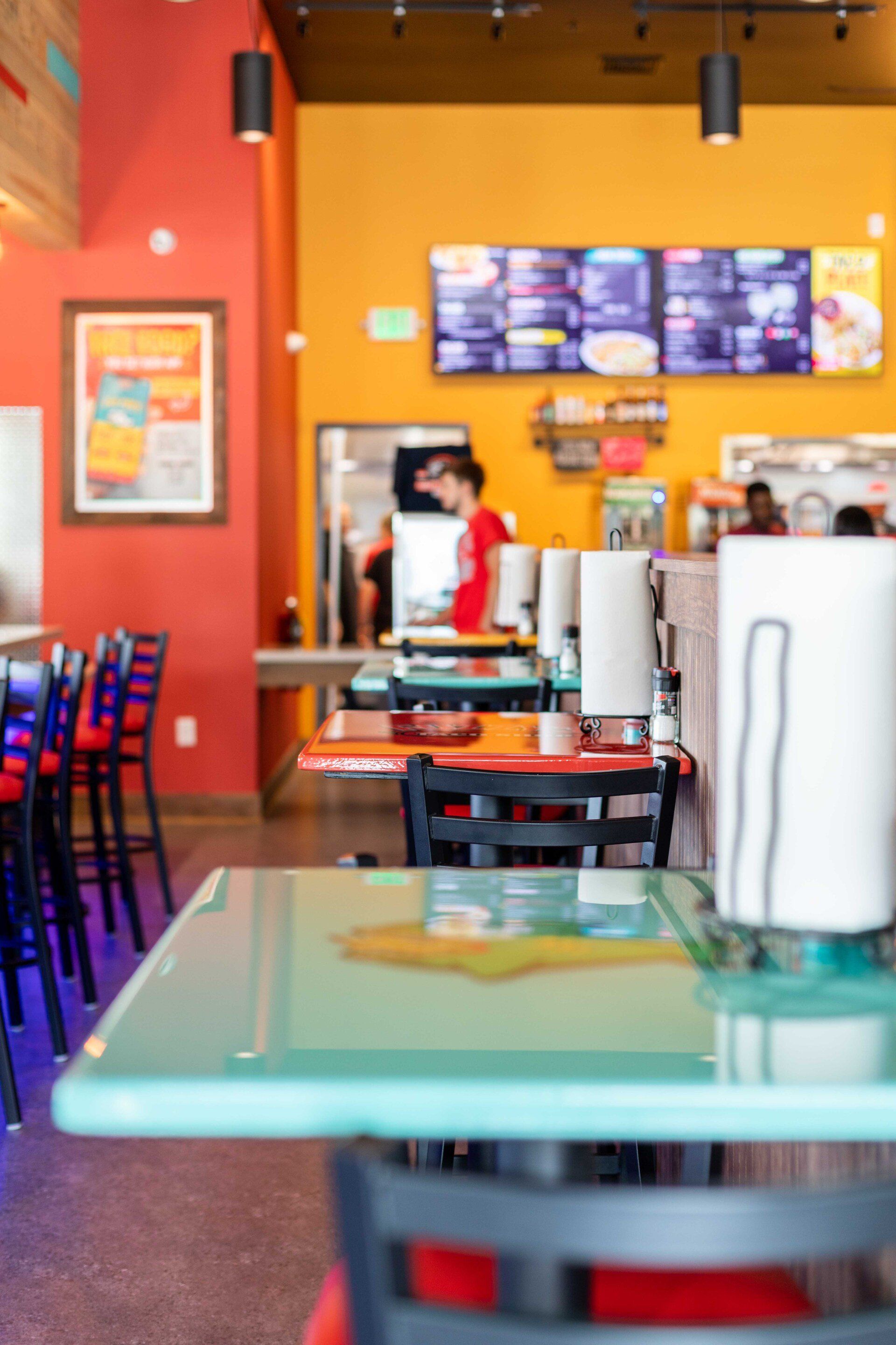 A restaurant with tables and chairs and a menu on the wall