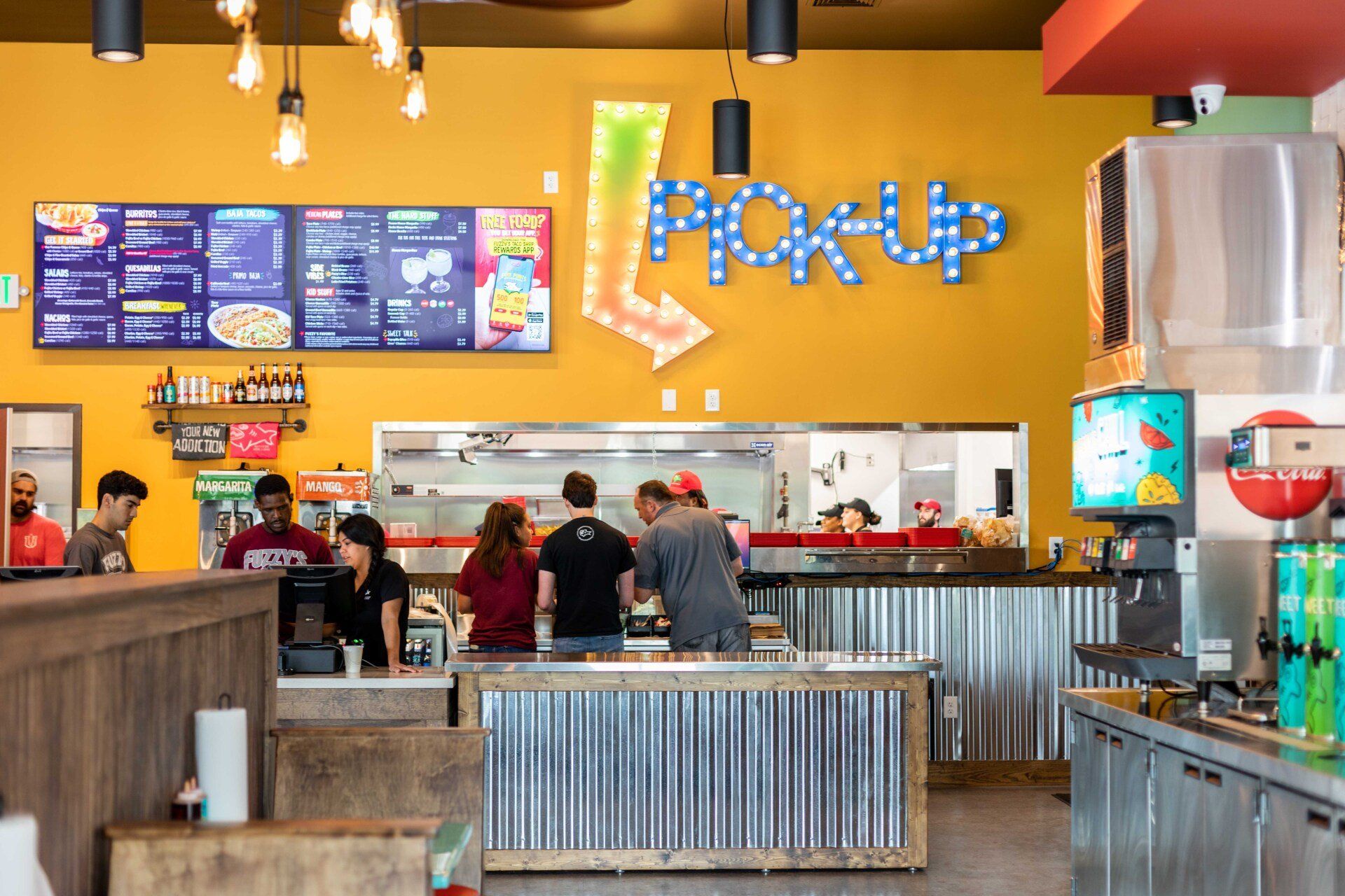 A group of people are standing at a counter in a restaurant.