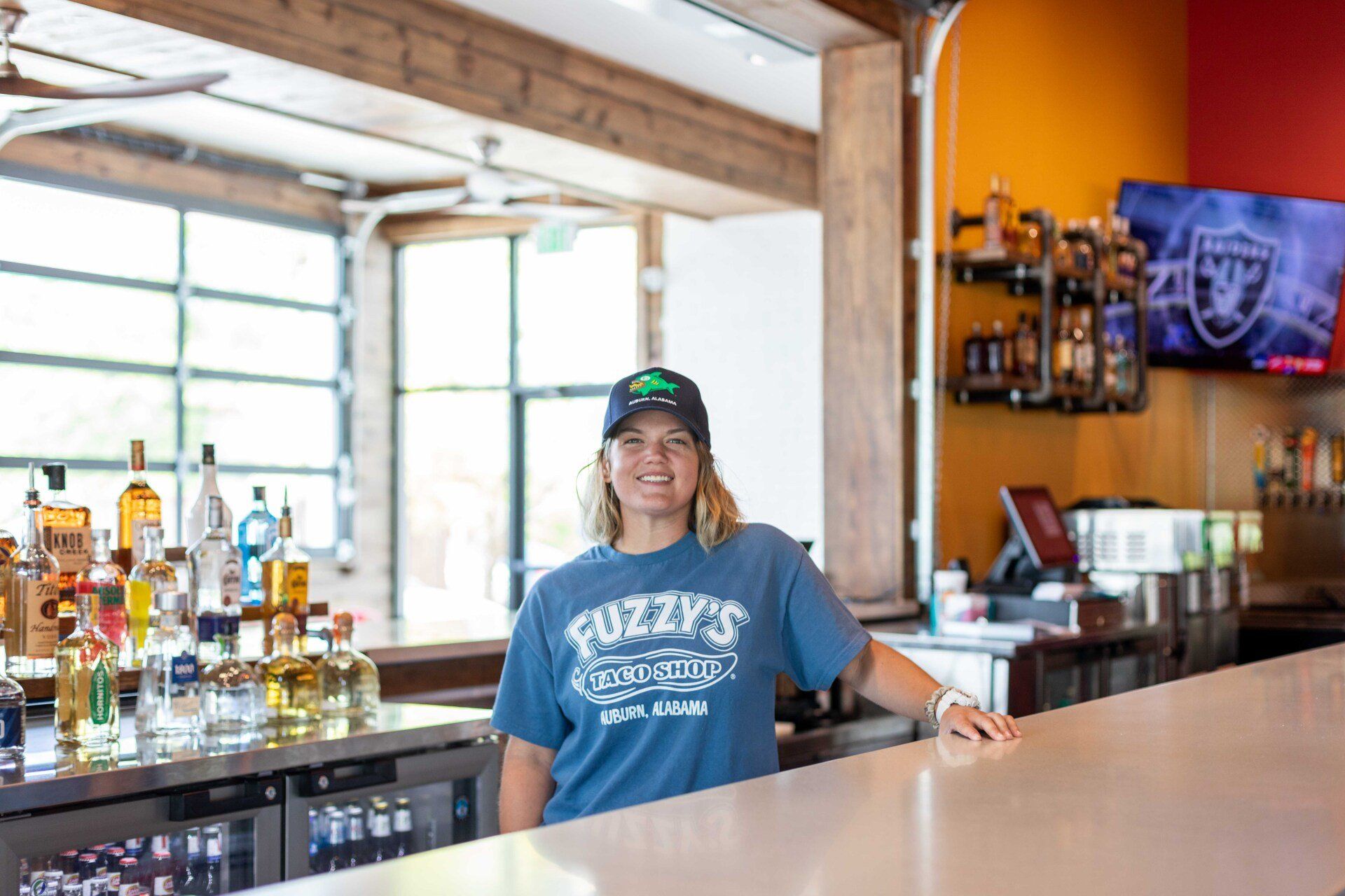A woman in a blue shirt is standing behind a bar.
