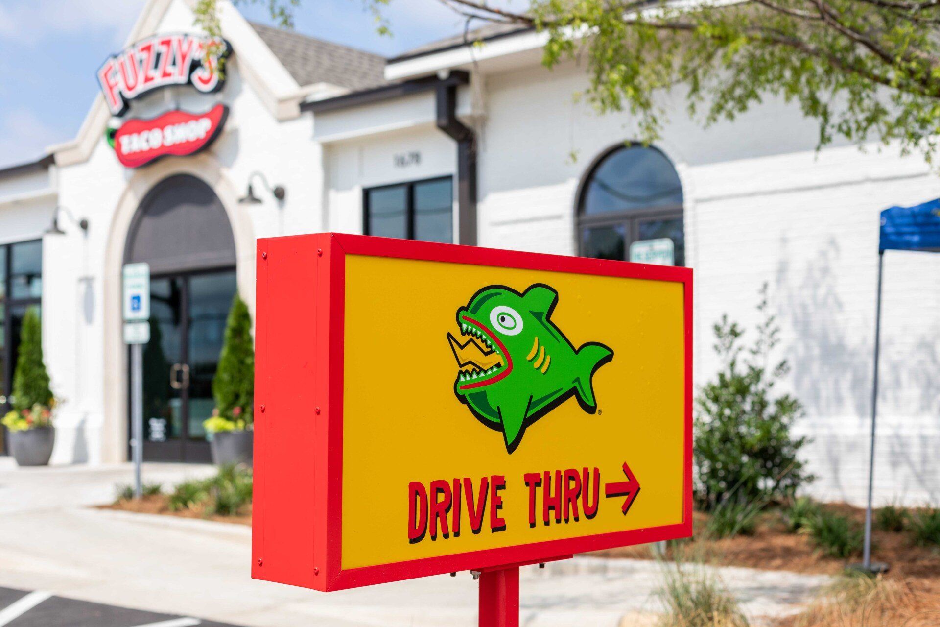 A drive thru sign with a green fish on it is in front of a restaurant.