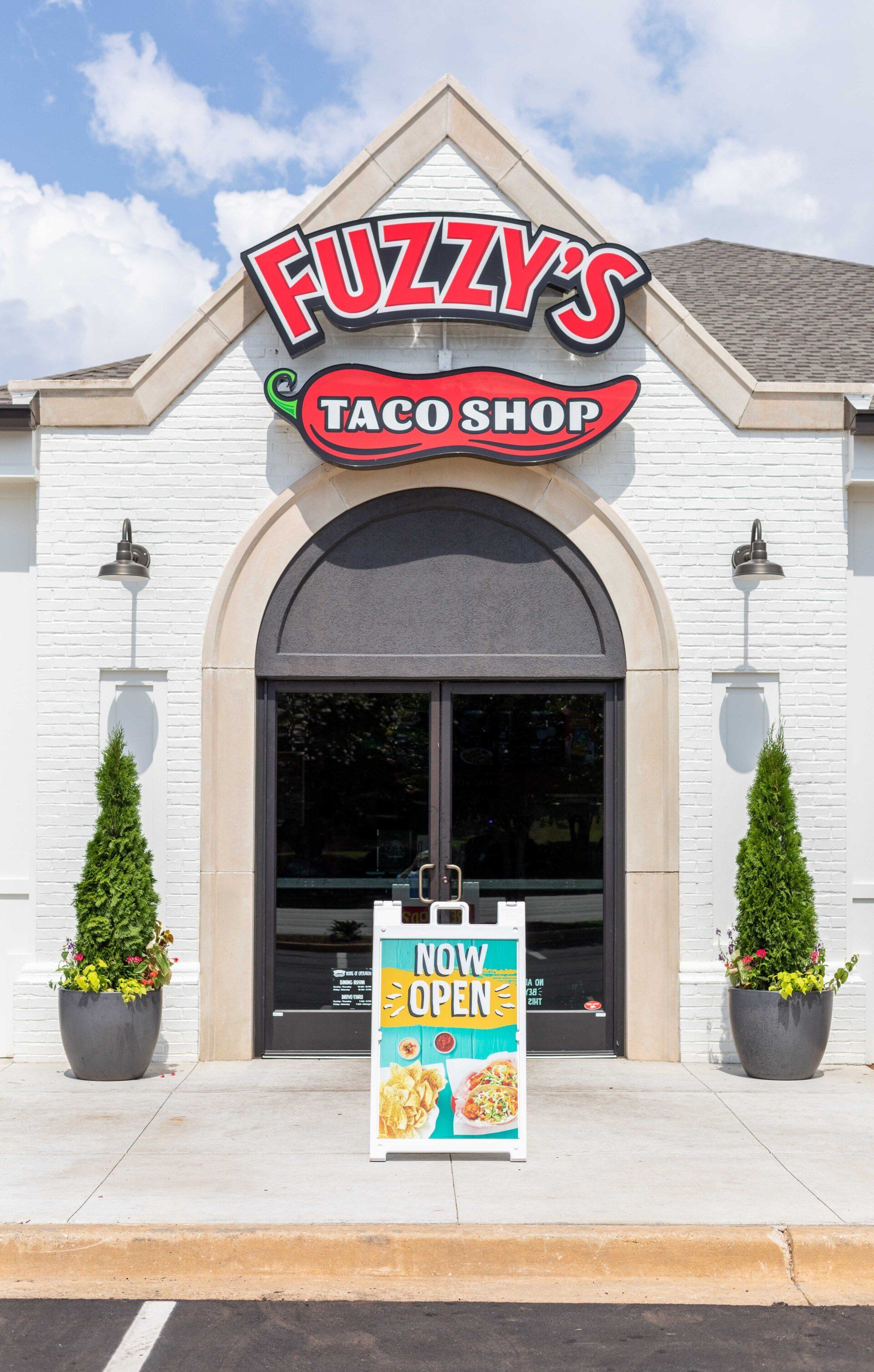 The front of a fuzzy 's taco shop with a sign in front of it.