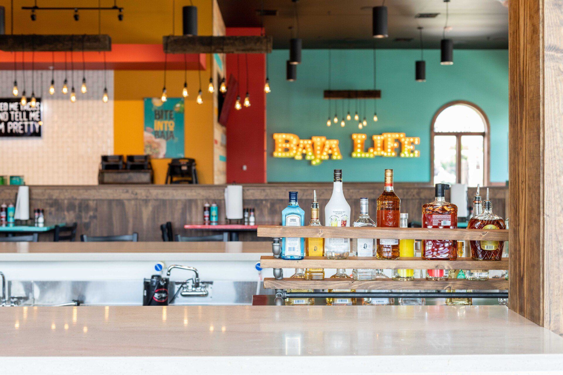 A bar in a restaurant with a sign that says baja life on the wall.