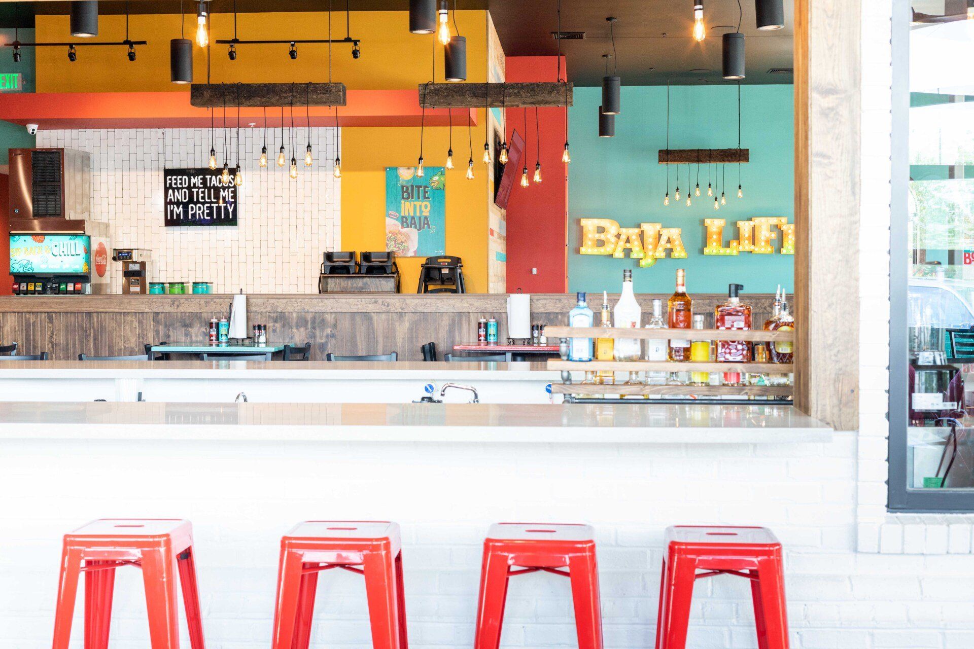 A bar with red stools and a sign that says baja life