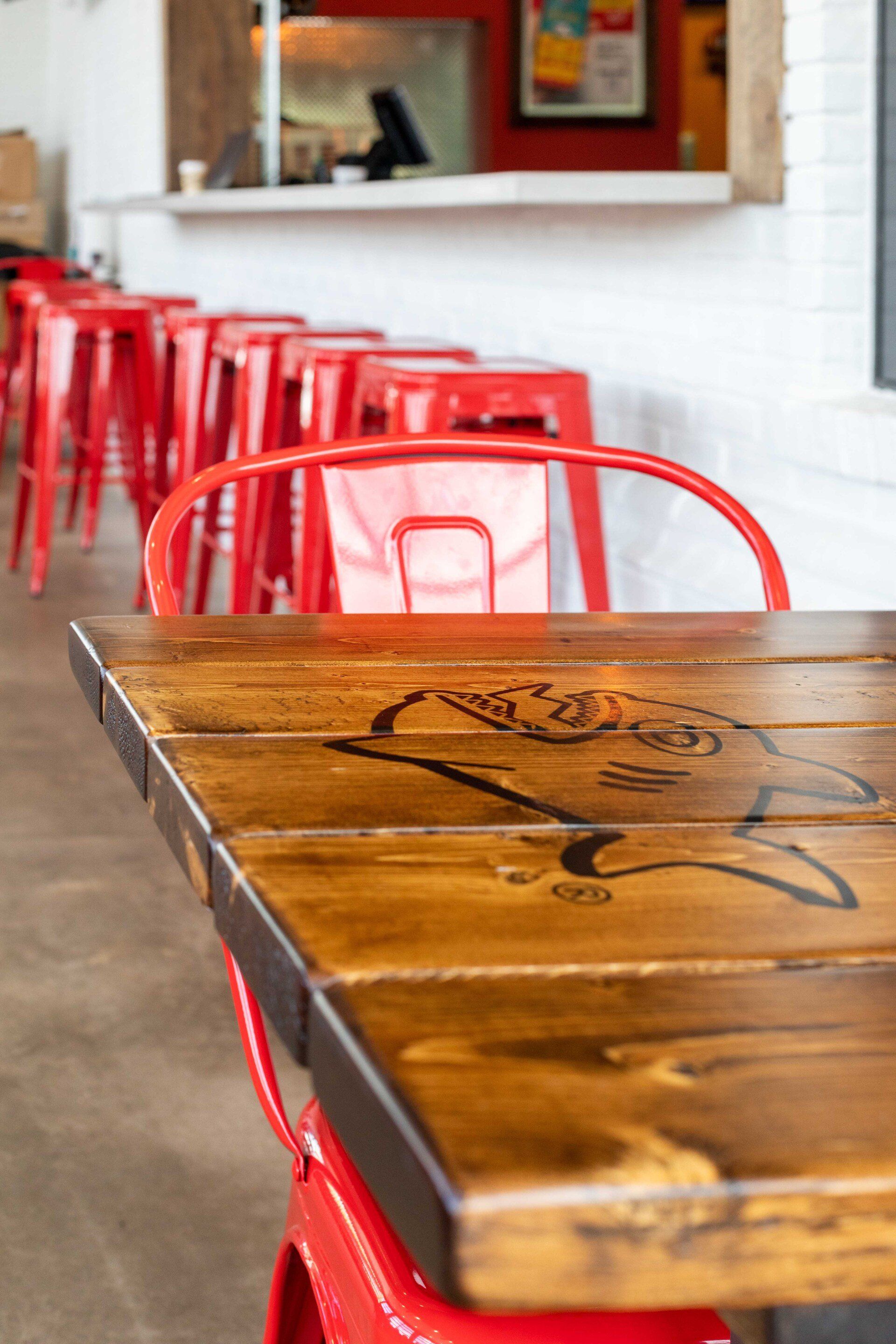 A wooden table with red chairs in a restaurant.
