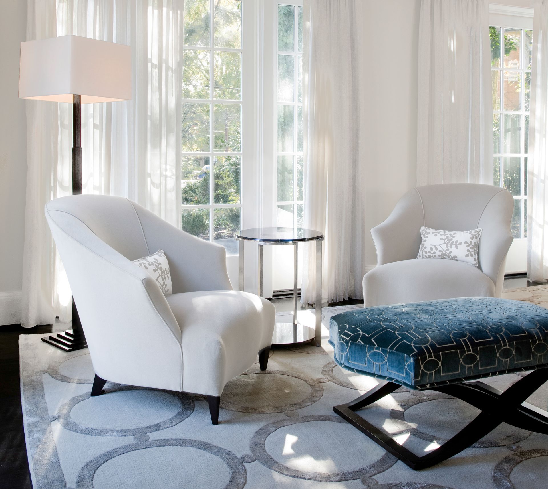 A cozy library with wooden shelves, a fireplace, and two cream-colored armchairs facing each other.