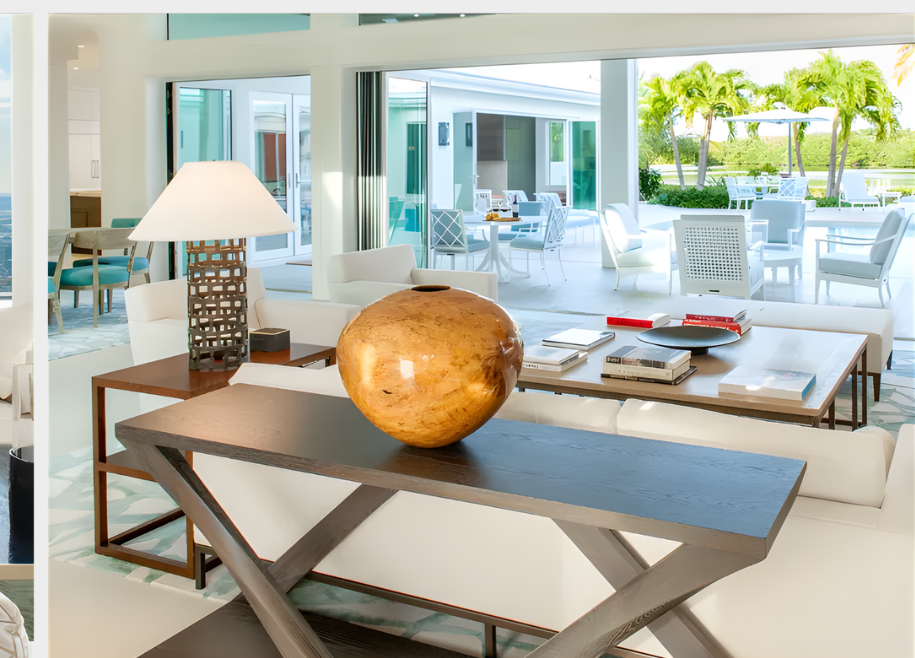 Living room with open doors to a patio, white furniture, a decorative vase, and a lamp.