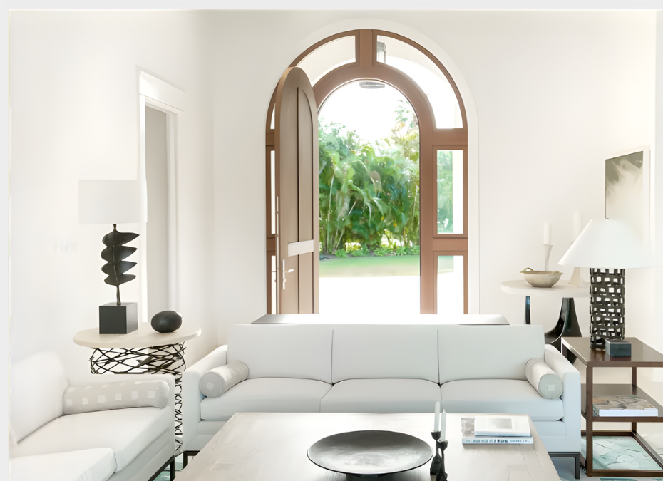 White living room with an open arched door, revealing a bright green outdoors.