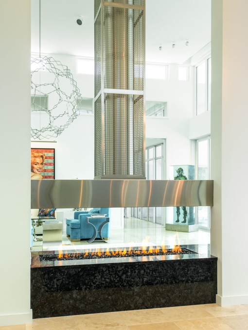 Modern fireplace with flames, stainless steel accents, and a granite base. Interior design.
