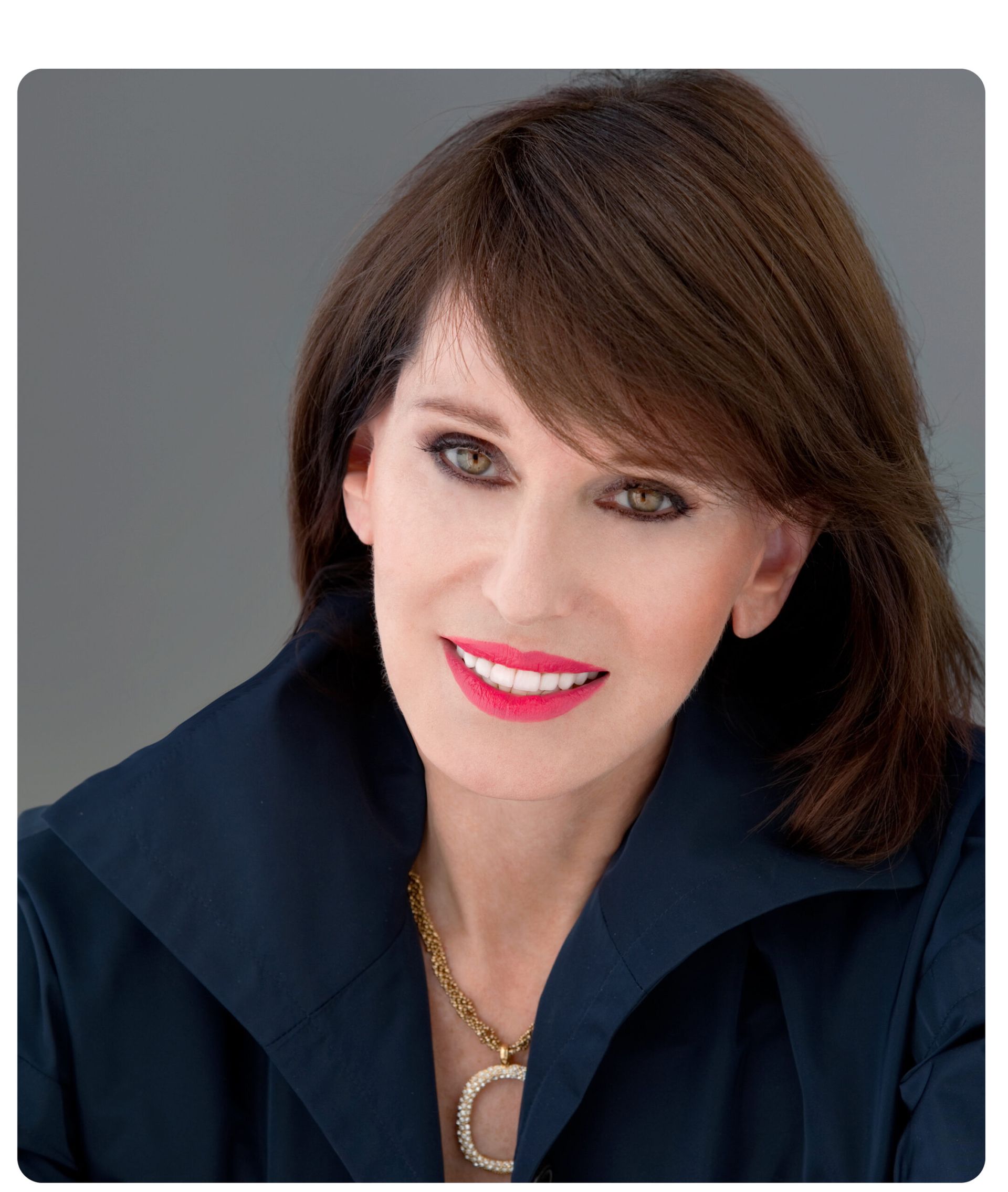 Woman with dark hair and a navy blue jacket, smiling.