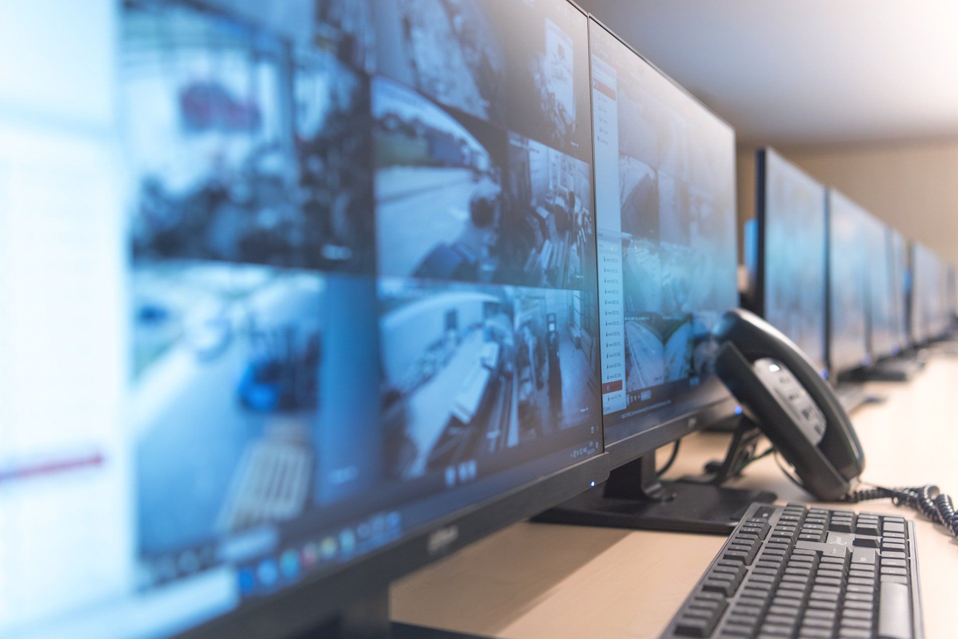 A row of computer monitors and a keyboard on a desk.