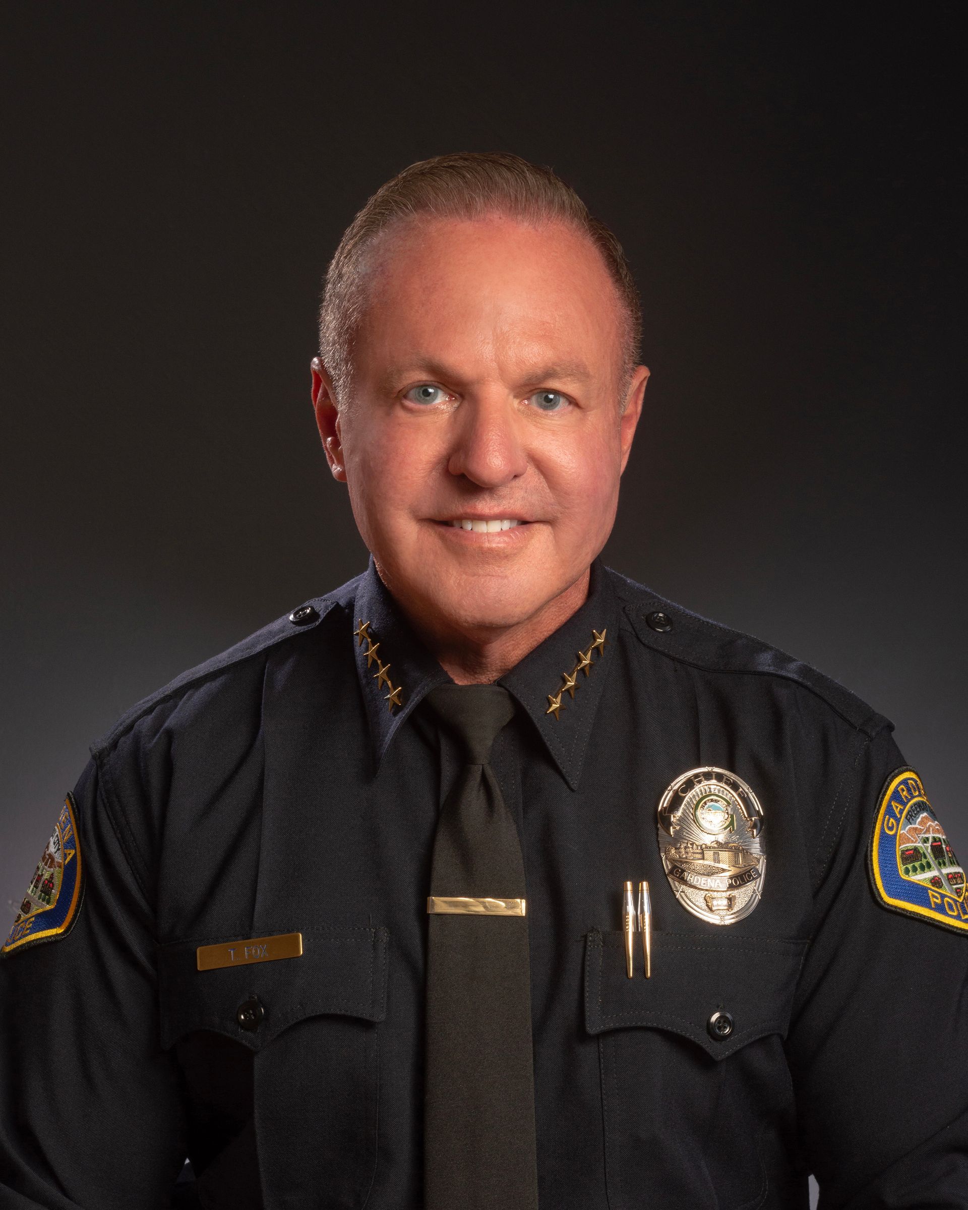 A man in a police uniform and tie is smiling for the camera.