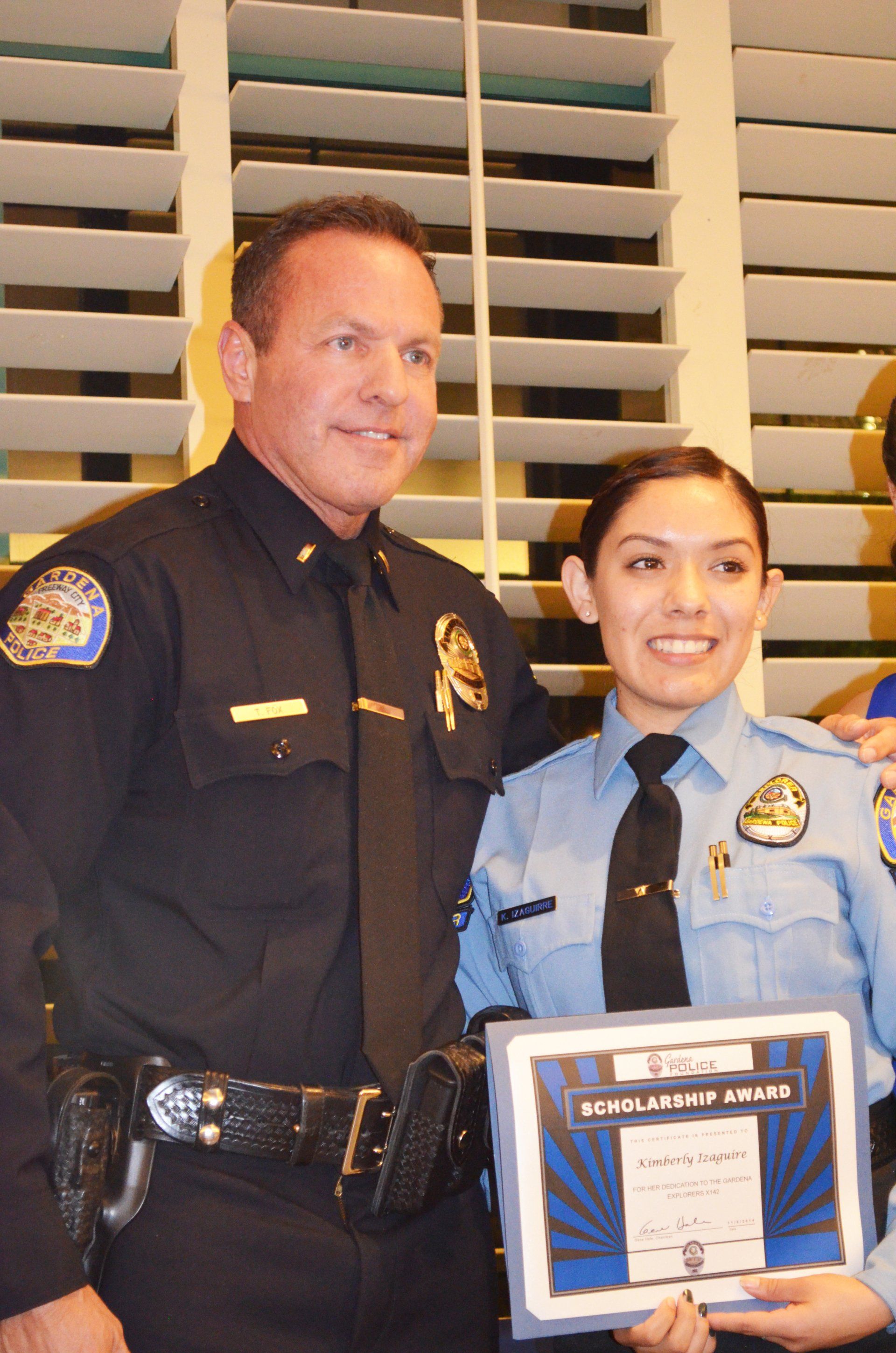 A man and a woman in police uniforms holding a certificate