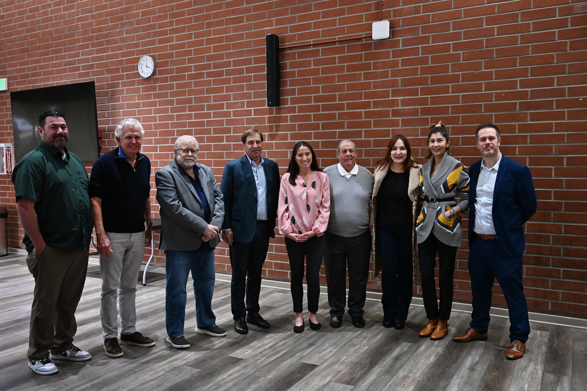 A group of people are posing for a picture in front of a brick wall.
