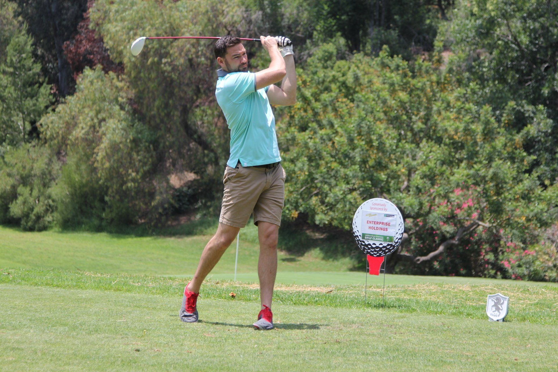 A man is swinging a golf club on a golf course.