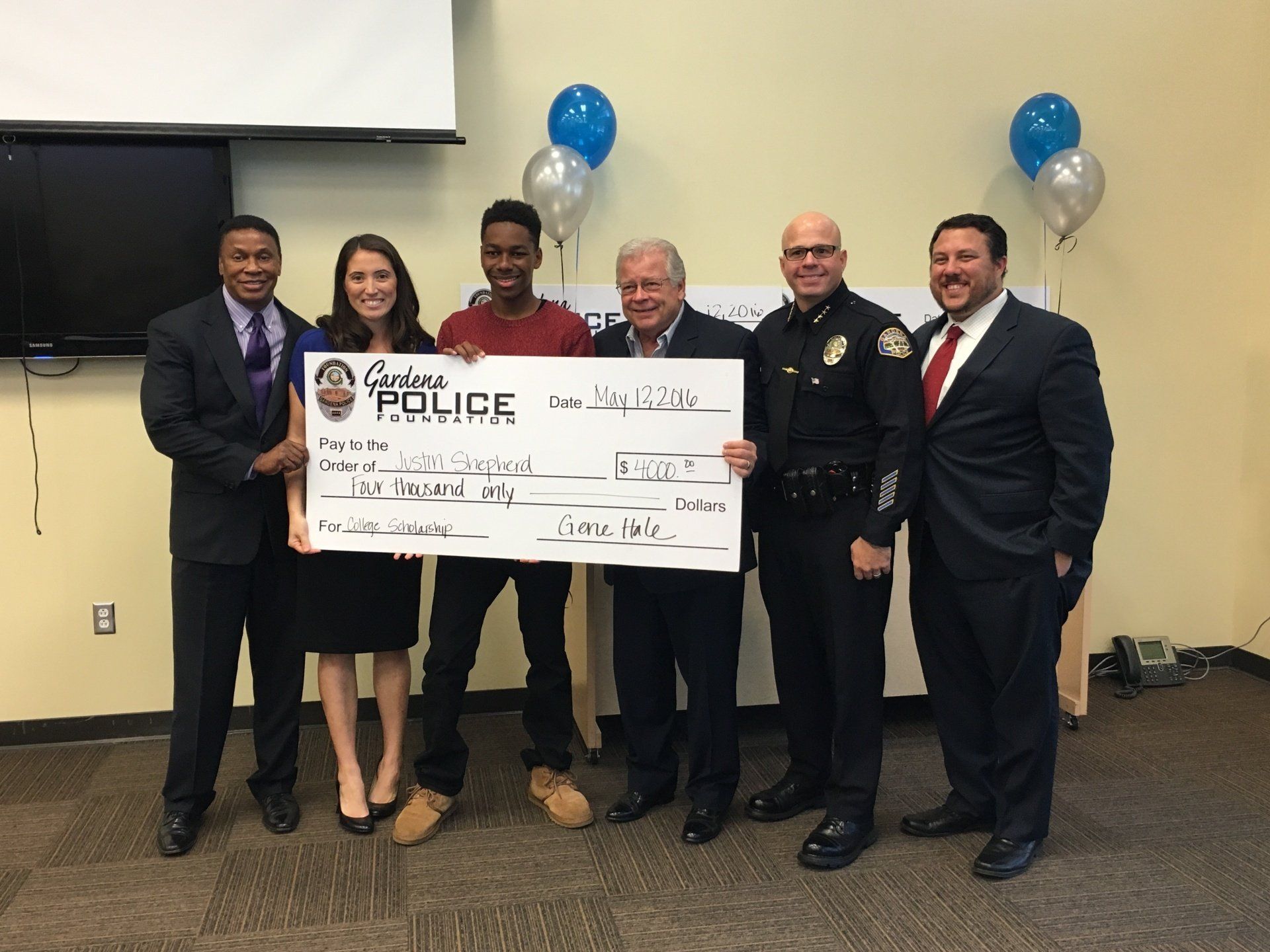 A group of people standing next to each other holding a large check that says police on it.