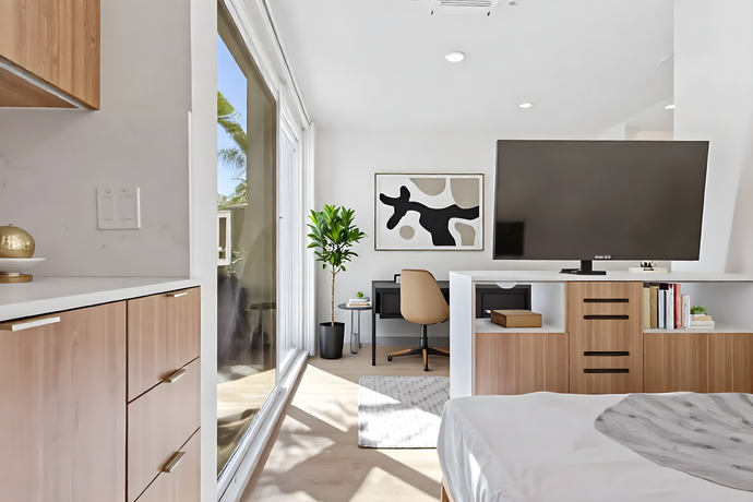 A bedroom with a large flat screen tv and a desk