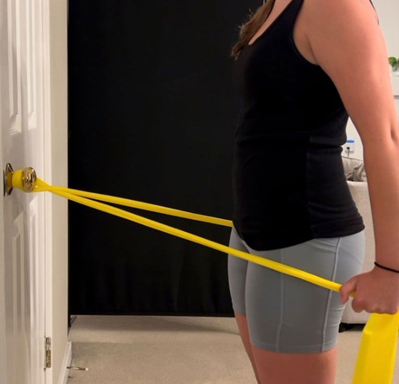 A man is being helped by a doctor to lift a dumbbell.