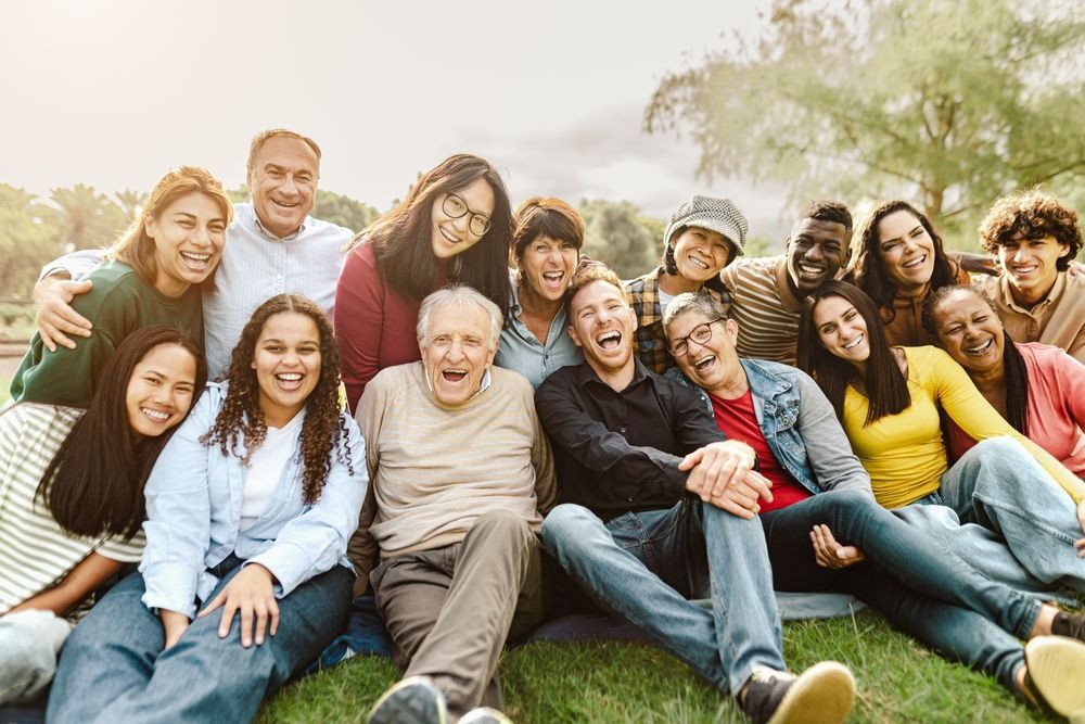 A large group of people are sitting on the grass in a park.