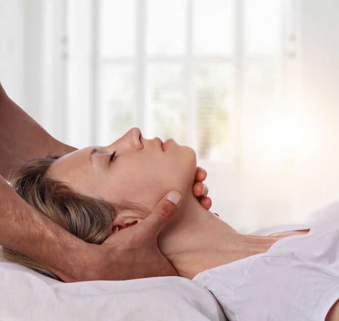 A woman is laying on a bed getting a massage from a man.