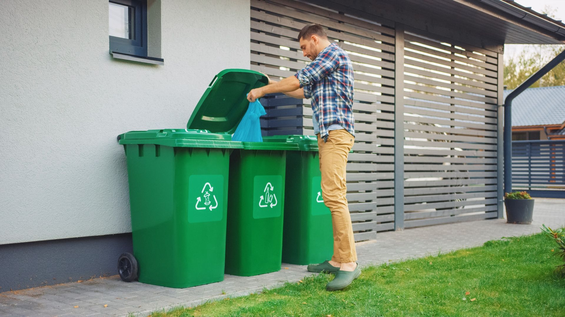 A man is putting a tire in a recycling bin.