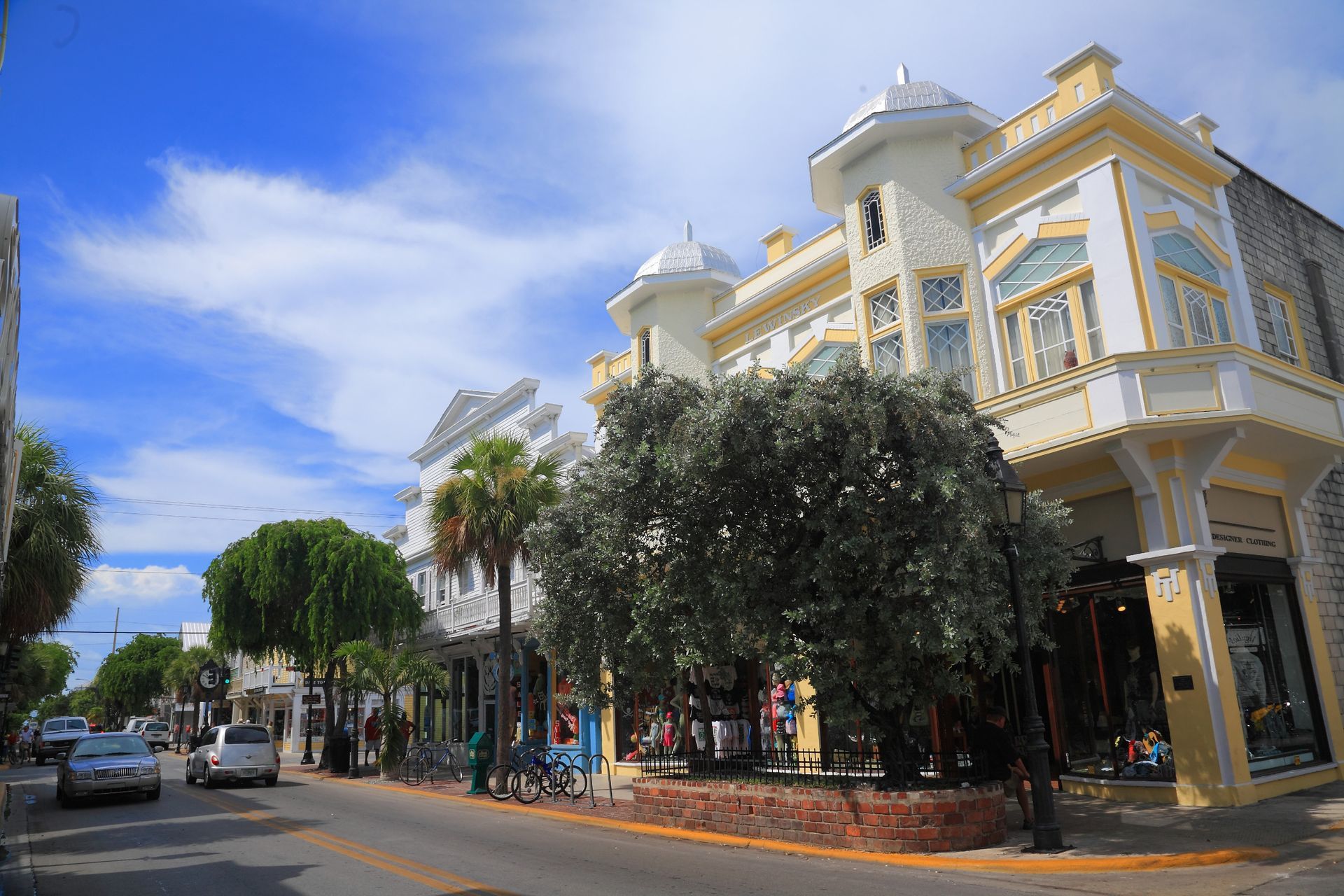 A city street with a lot of buildings and trees on a sunny day.