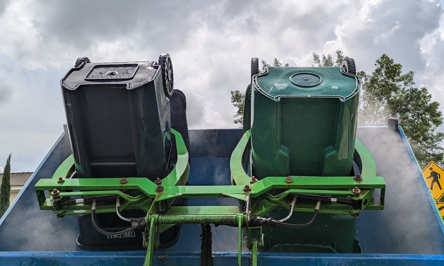 Two green garbage cans are sitting on top of a blue dumpster.