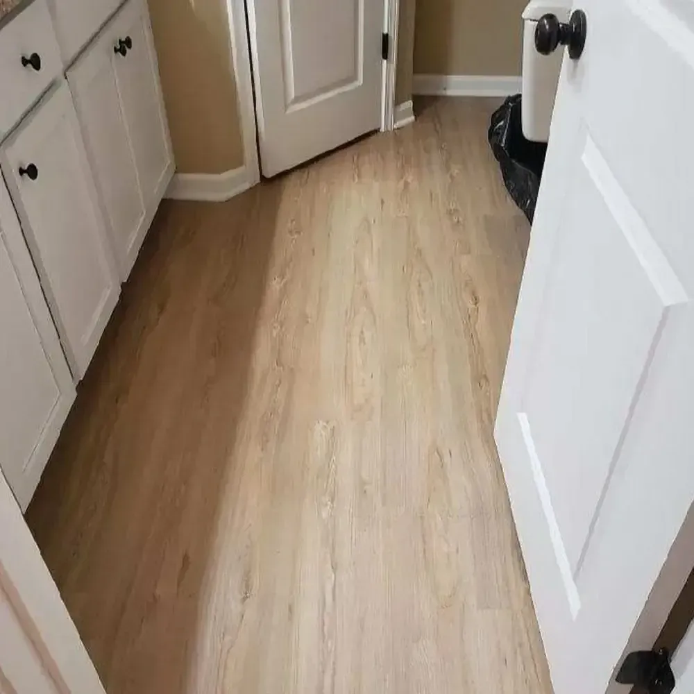 Bathroom with light wood-look flooring. White cabinets and door frame the scene.