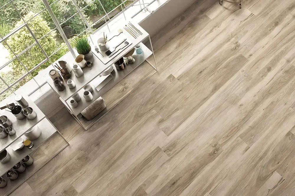 A wooden floor extends from a large window, with a built-in shelf displaying various decorative items.