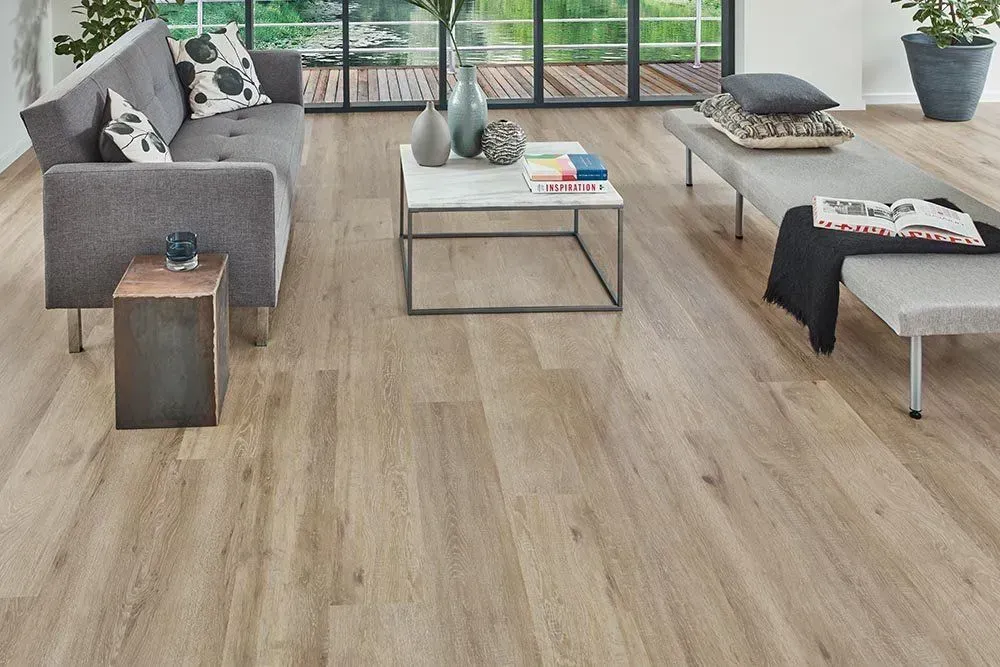 A modern living room with light wood flooring, gray sofa, and a marble-topped coffee table.