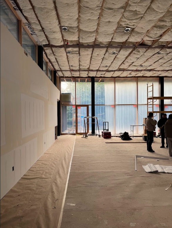 A group of people are standing in an empty room with insulation on the ceiling