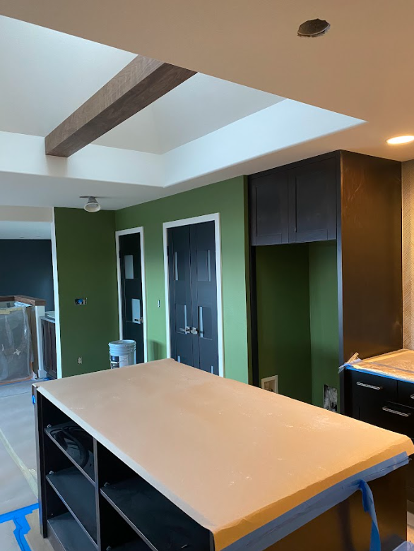 A kitchen with green walls and a large island in the middle.