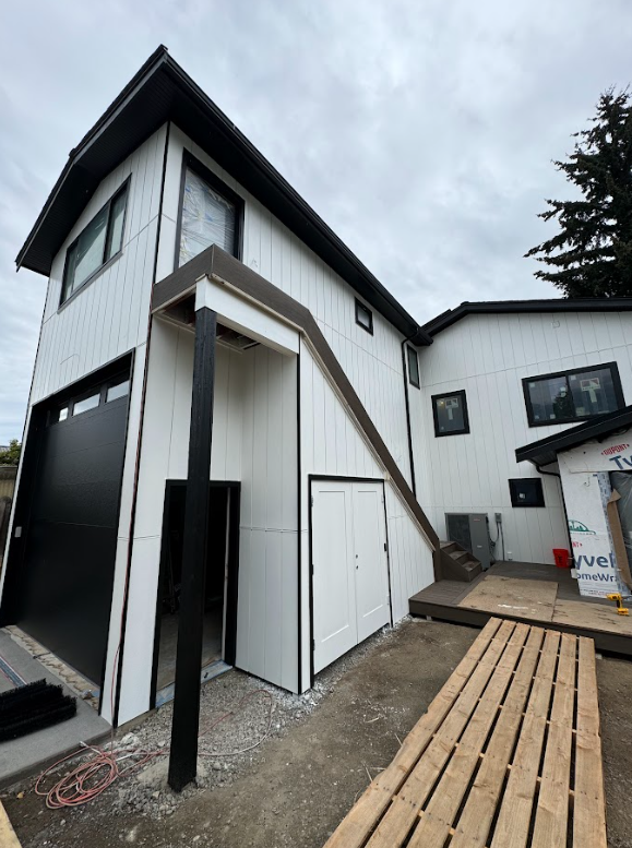 A large white house with stairs leading up to the second floor.