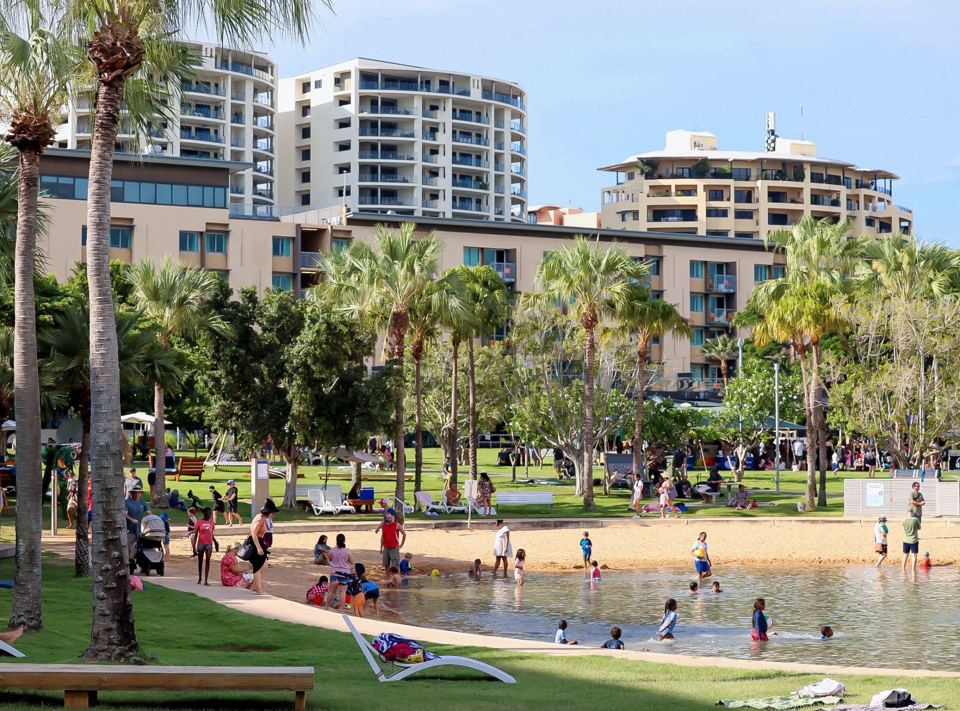 Group of people enjoying the sand and the water at the waterfront. Apartments and high rise buildings are in the background