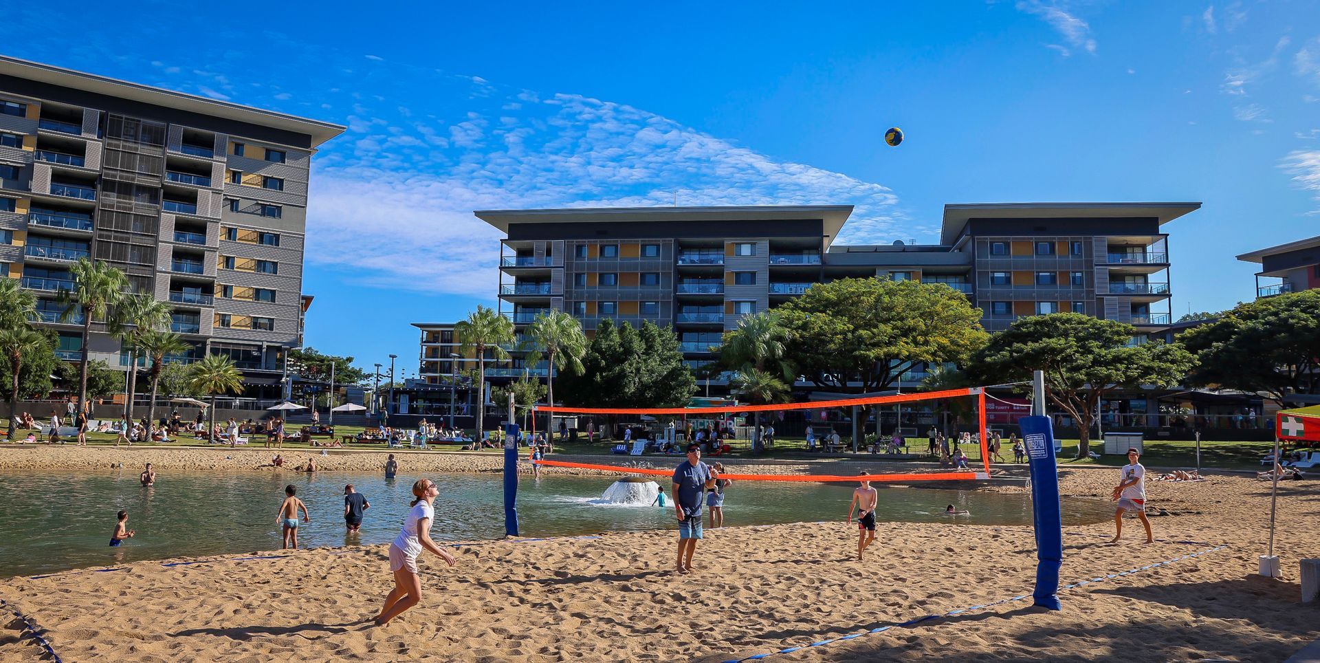 People are playing beach volleyball, the water is in the background.