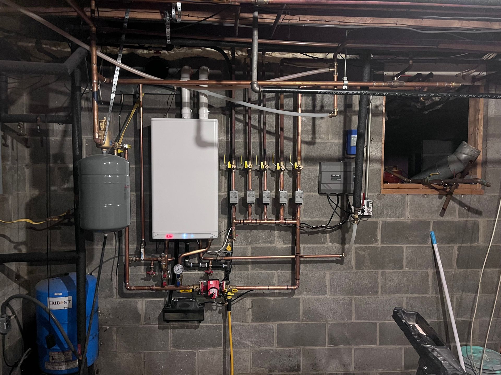A basement with a boiler and pipes hanging from the ceiling