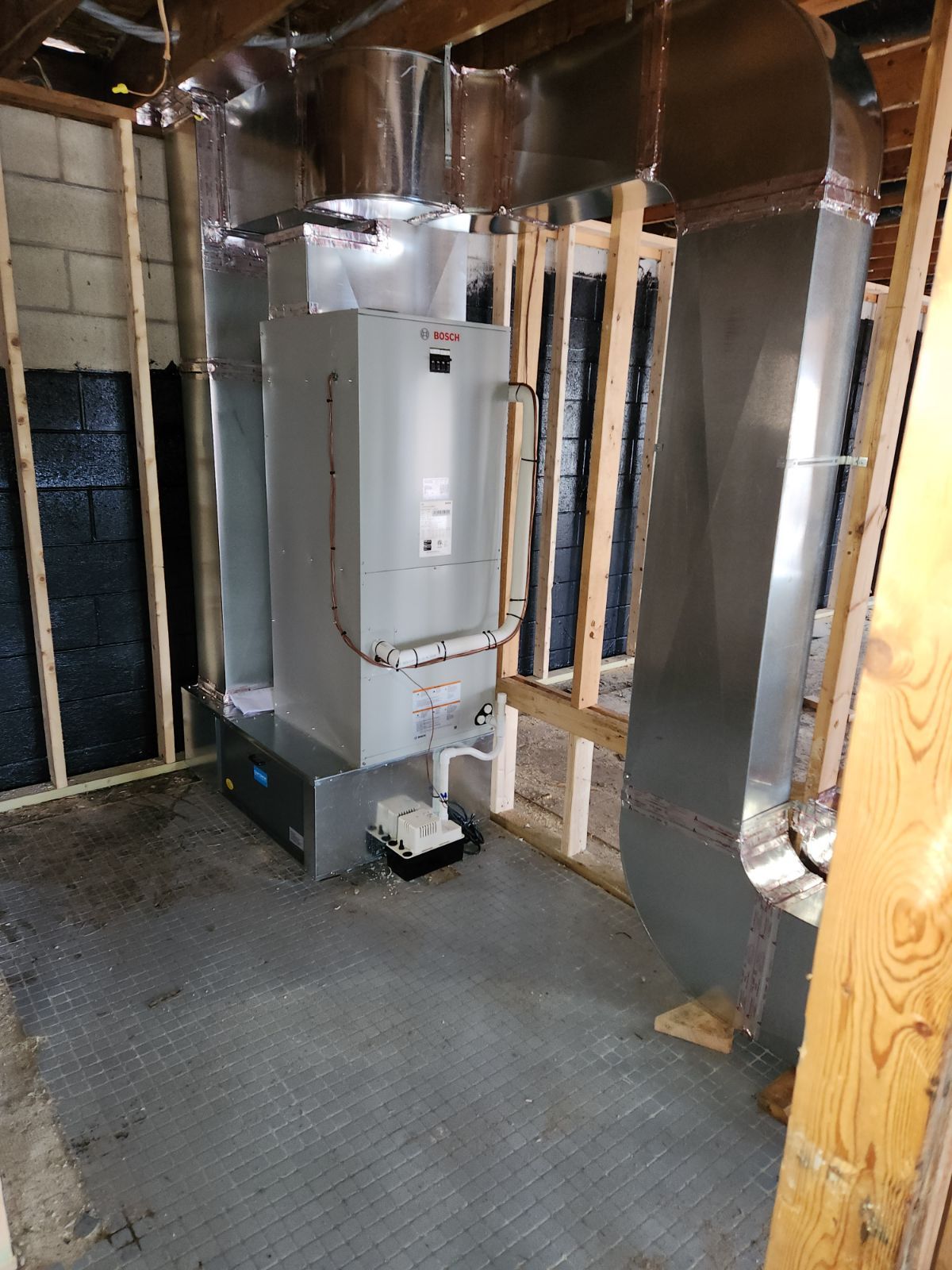 A room with a heater and ducts coming out of it.