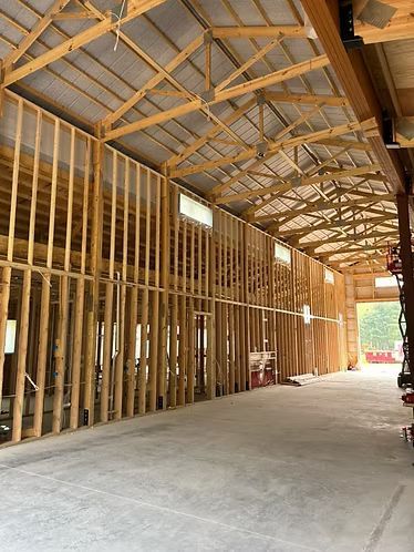 Interior of a wooden barn under construction with exposed framing and concrete floor