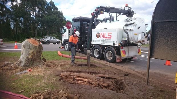 A man is standing next to a vacuum truck that says nils on the side.