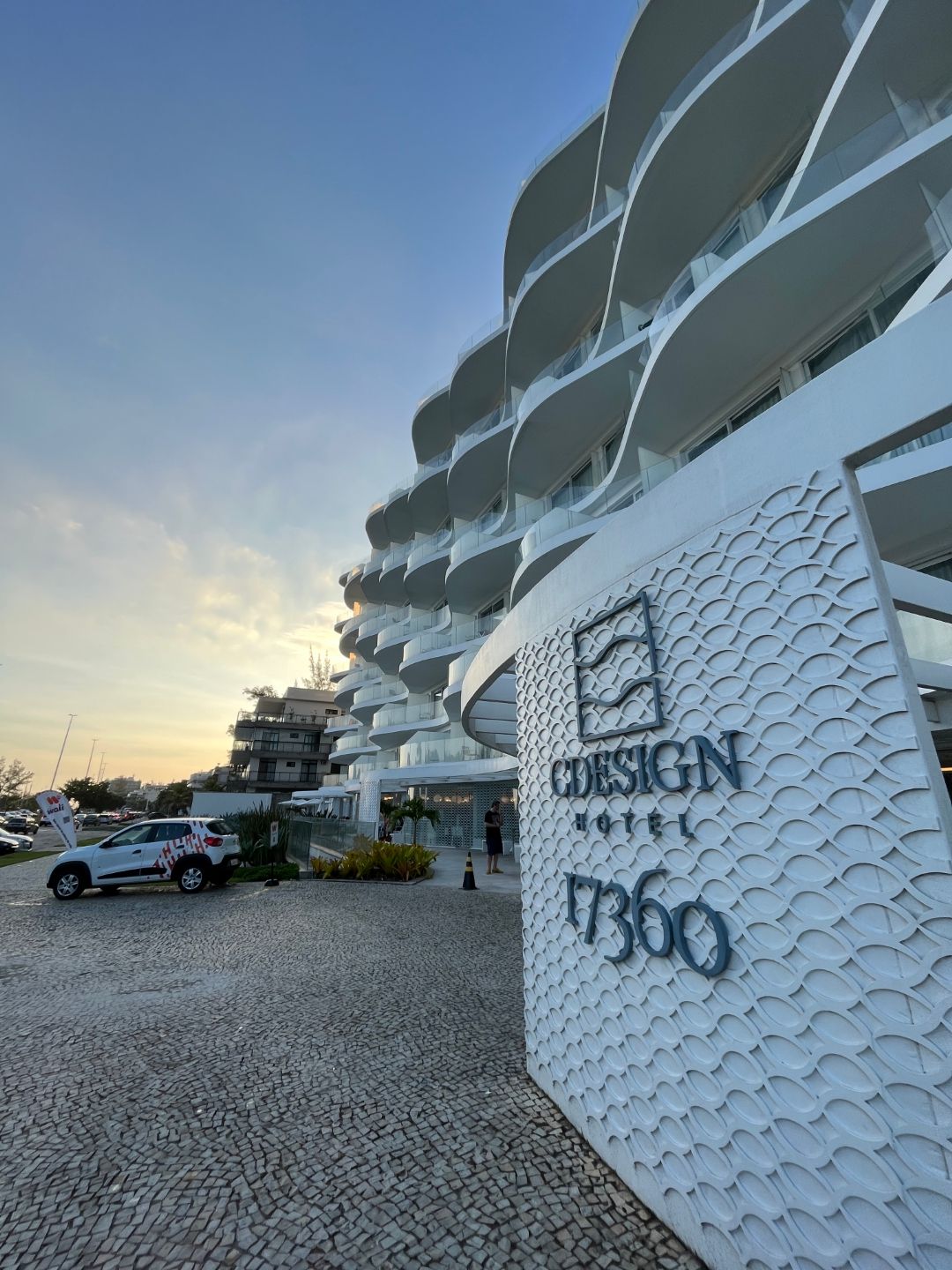 Um grande edifício branco com carros estacionados na frente dele.