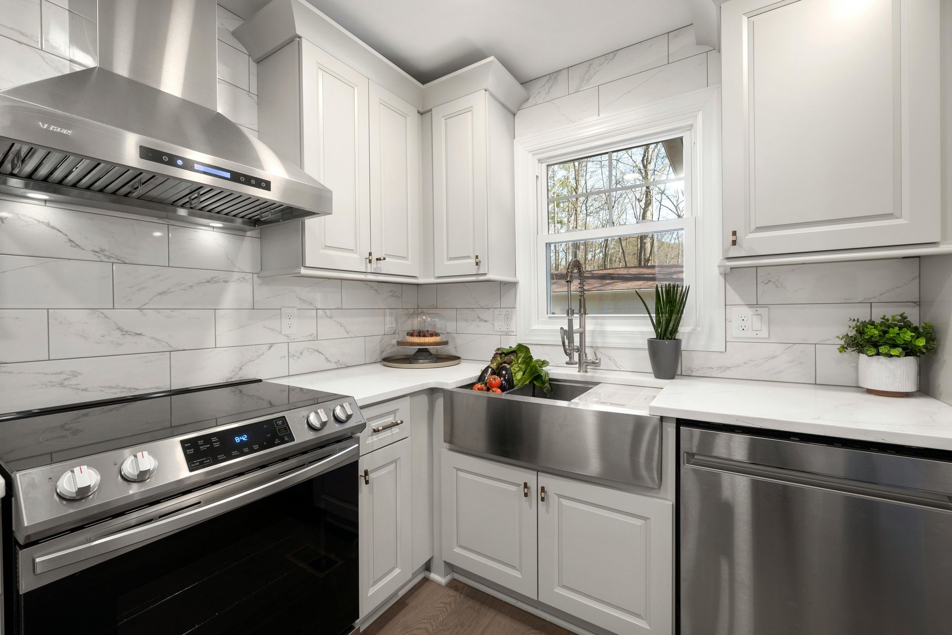 Modern kitchen with white cabinets, stainless steel appliances, a farmhouse sink, and white subway tile backsplash.