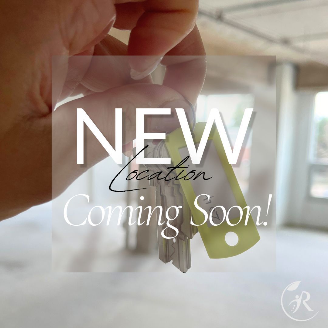 A person is holding keys in front of a sign that says new location coming soon