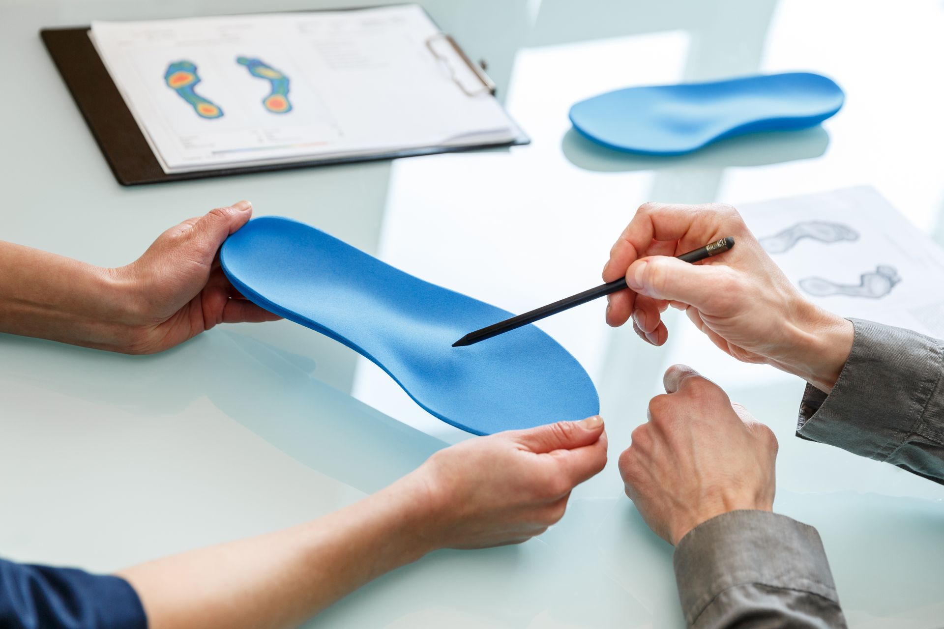 A person is pointing at a blue insole with a pen.