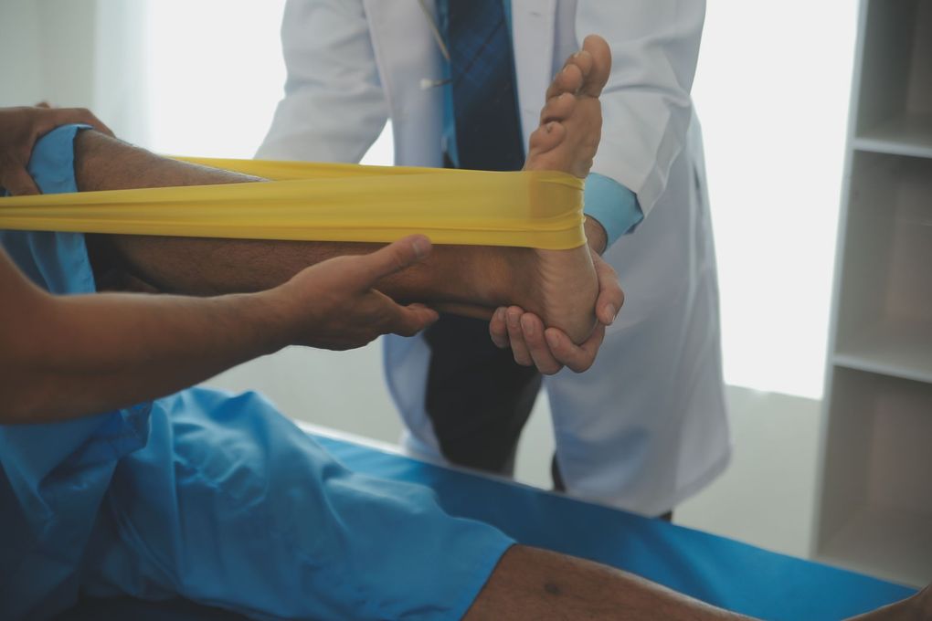 A doctor is stretching a patient 's leg with a rubber band.